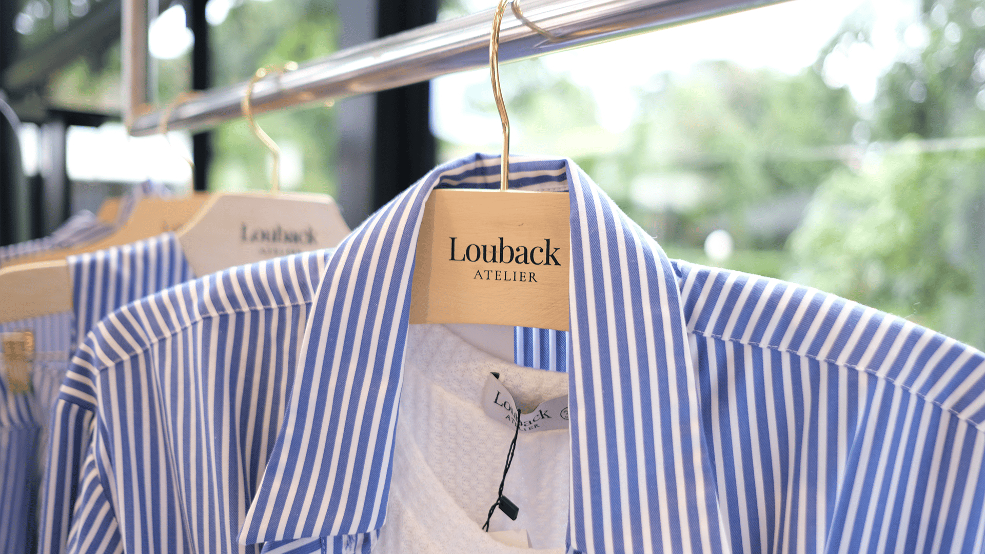 Camisa listrada azul em cabide de madeira com a marca Louback Atelier